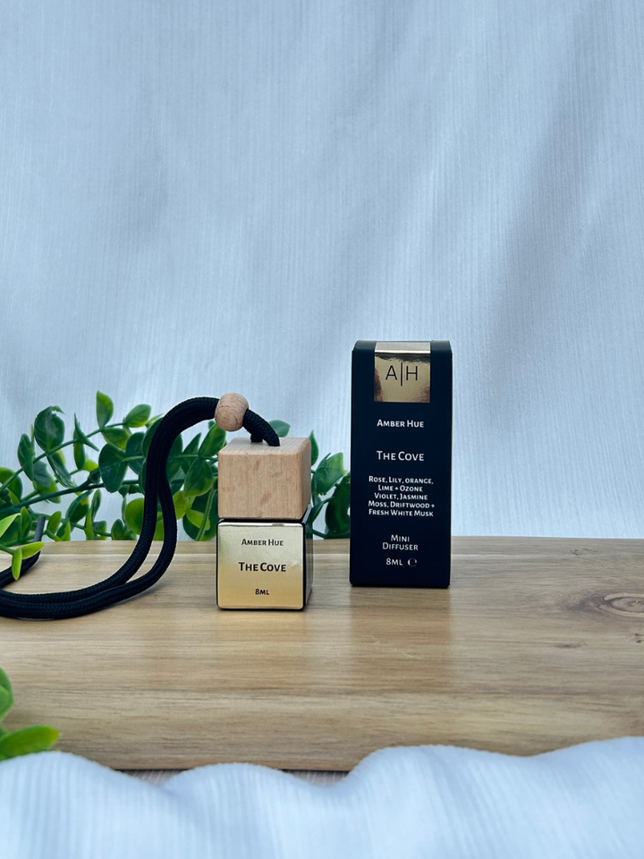 Two bottles of 'The Cove' by Amber Hub on a wooden surface with a light blue background.